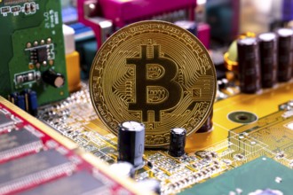 Virtual cryptocurrency money Bitcoin golden coin on a computer printed circuit board PCB. The