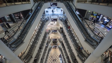 High angle shot of modern multistorey shopping mall. People traffic on the escalators of each floor