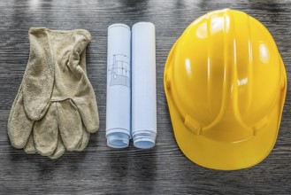 Safety gloves blueprints hard hat on wooden board