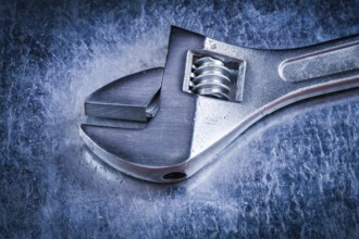 Metal adjustable spanner on scratched metallic background construction concept