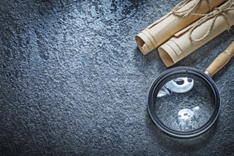 Vintage paper rolls magnifying glass on black surface