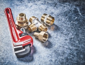 Pipe wrench brass hose nipples on scratched metallic background plumbing concept