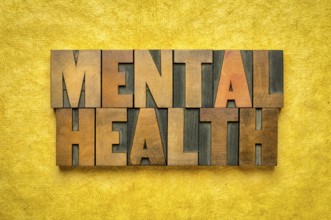 Mental health word abstract in vintage letterpress wood type printing blocks against yellow