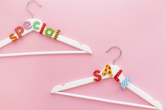 Creative top view flat lay white hangers special sale text pastel pink background copy space