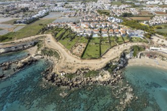 Drone aerial of holiday village with luxury houses at an idyllic rocky coast. Summer vacations at