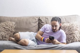 Portrait of gay man lying on sofa with mobile phone