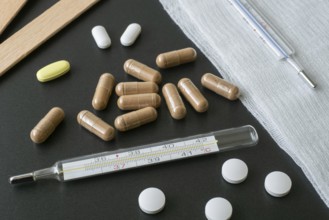 Traditional medical thermometer for measuring body temperature. Pills and medicaments on background