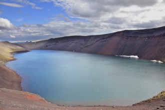 Oval blue lake in the crater of the volcano cooled down. Steep banks of the lake of red rhyolite.