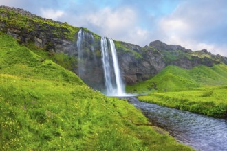 The warm July day in Iceland. Seljalandsfoss waterfall. Rainbow decorates drop of water