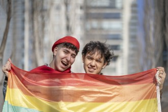 Young gay couple in a park holding lgbt rainbow flag