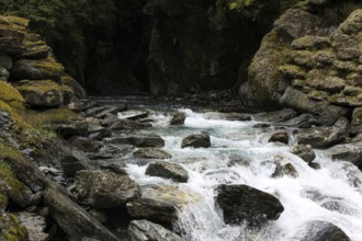 Small waterfall flows out of a dark cave