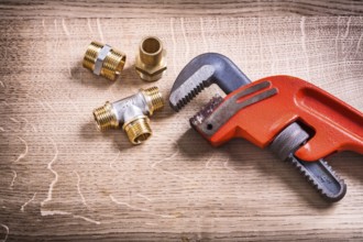 Plumbing Tools Composition Of Brass Pipe Connectors On Wooden Board and Monkey Wrench