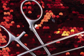 Detailed view of surgical instruments on shimmering red sequins