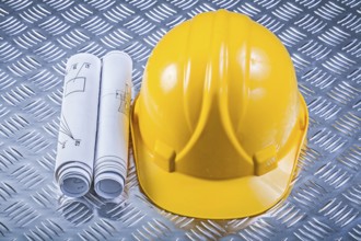 Rolled blueprints hard hat on grooved metal sheet construction concept