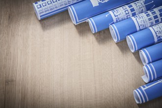 Pile of blue rolled up construction drawings on wooden board