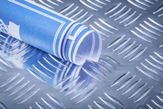 Blue rolled blueprints on corrugated metal background construction concept