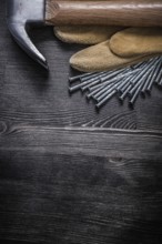 Working gloves construction nails claw hammer on vintage wooden board