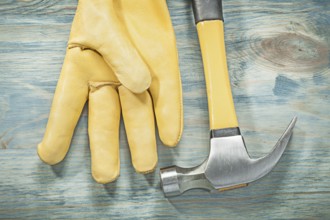 Top view of claw hammer leather protective glove on wooden board construction concept