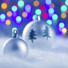 Christmas silver baubles witn tree and burred lights background