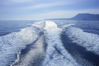 Fishing speedy boat prop wash, white wake on the blue ocean sea