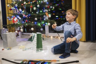 Happy boy opening a Christmas gift and Christmas tree in the background