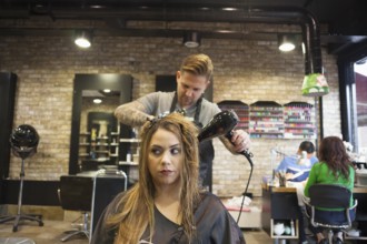 A Woman having her hair blowdried in hipster barbershop