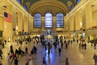 People moving through a large railway station concourse under a cool glow of light, Manhattan,