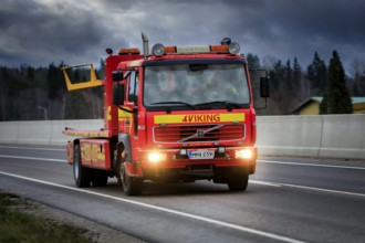 Volvo tow truck of Halikon Hinaus driving along Highway 52 under dramatic sky on a dark winter