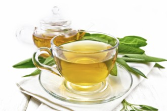 Herbal tea with sage in a glass cup on a towel on wooden board background
