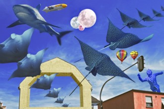 Whimsical composing, bare facades and traffic lights in front of blue with manta rays and rays,