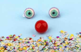 Red Nose with confetti over light blue background. Conceptual Photo to use for all funny