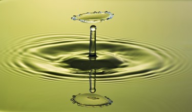 Gravity Dancing drop of water on a green background