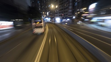 Traveling through the night city by double-decker tram. View to the rails and transport on the road