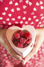 Woman in red dress holding a cup of raspberries