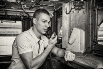 Black and White Retro Close Up of Young Man Speaking into Handheld Radio in Engine of Old Fashioned