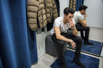 Young Handsome Man Trying on Clothes in Clothing Store's Changing Room in Front of a Mirror or in