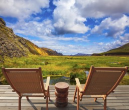 Two comfortable wooden chairs and small table stand for tired tourists. Volcanic summer tundra.
