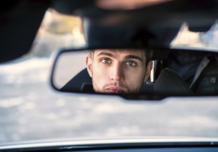Handsome Blond Young Man Driving a Car, Wearing Black Sweater. hand on wheel