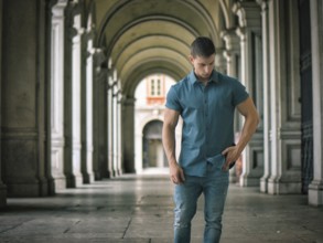 Handsome muscular young man standing outside in city setting looking to a side