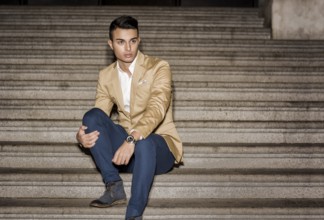 Elegant attractive young man outdoor wearing business suit, in European city on old stairs