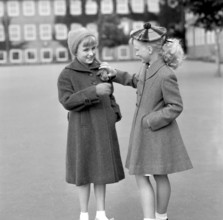 Girls in the 1950s. Two teenage girls dressed in outfits typical of the decade. Both in warm coats