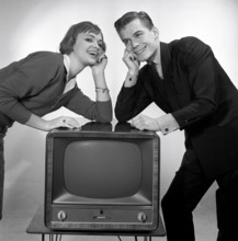 Television in the 1950s. A young couple is pictured beside a typical 50s television set. Photo