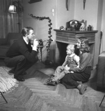 Amateur photographer in the 1940s A man is taking pictures of his wife and son at home. He is