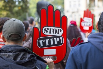 Activists are holding red hand signs Stop TTIP during a demonstration against Free Trade Agreements