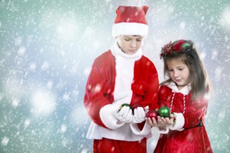 Couple of children holding christmas theme ornament on snowy background, Toronto, Canada, North