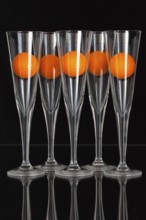 Five glasses of champagne and orange golf balls on the glass plate