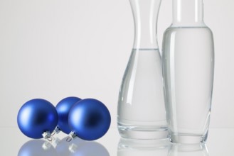 Two vases with clean water and Christmas decoration on a glass table