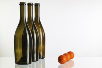 Empty three wine bottles and golf balls on a glass desk