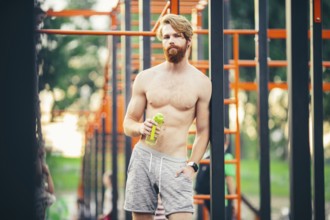 Thirst and health. Sportsman hold water bottle on stadium. Fit man with plastic flask outdoor. Stay