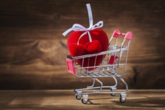 Red heart toy in shopping cart on vintage wood
